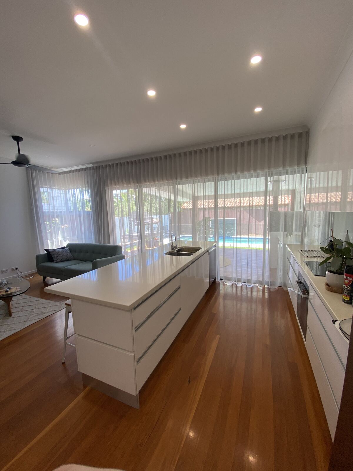 Sheer wave fold curtains across a kitchen and living area
